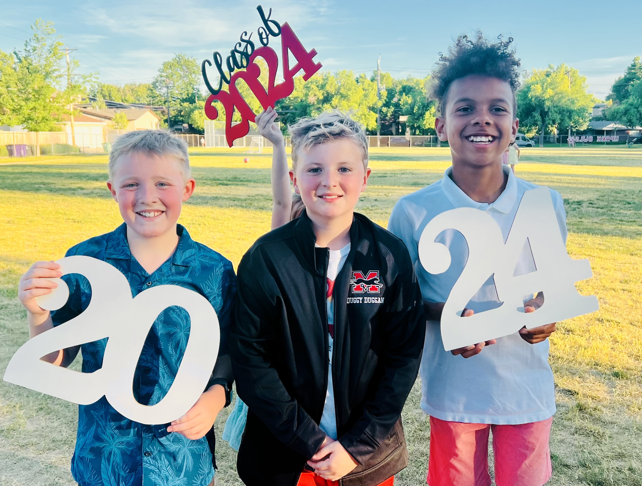 3 students holding class of 2024 signs